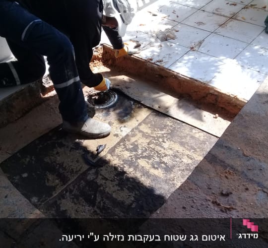 אדם עובד על איטום רצפה עם חומר שחור